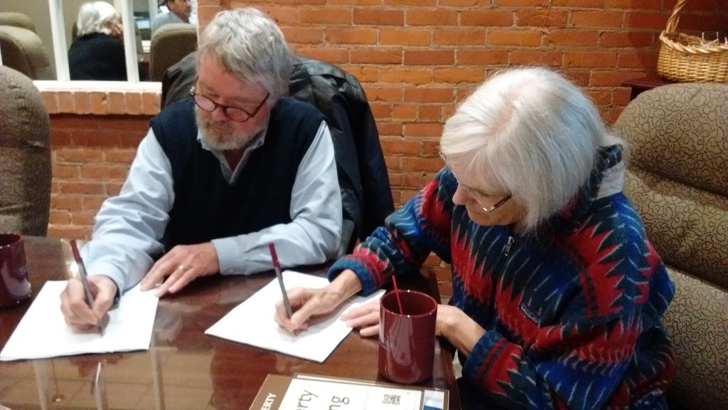 Dave Foster and Cathy Kamil sign the documents that protect their land. Photo by Remy Long.