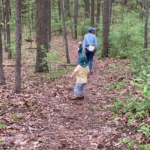 Allene and kids walking on a path in the forest.