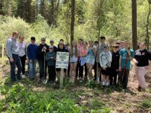 Stockbridge students stand with "I planted trees for clean water" sign at Beckwith Preserve