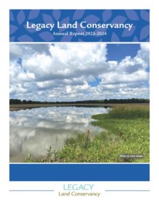 Legacy Land Conservancy Annual Report 2023-2024. Image of blue sky with white puffy clouds reflecting over water and wetland plants. Photo by Cara Green.