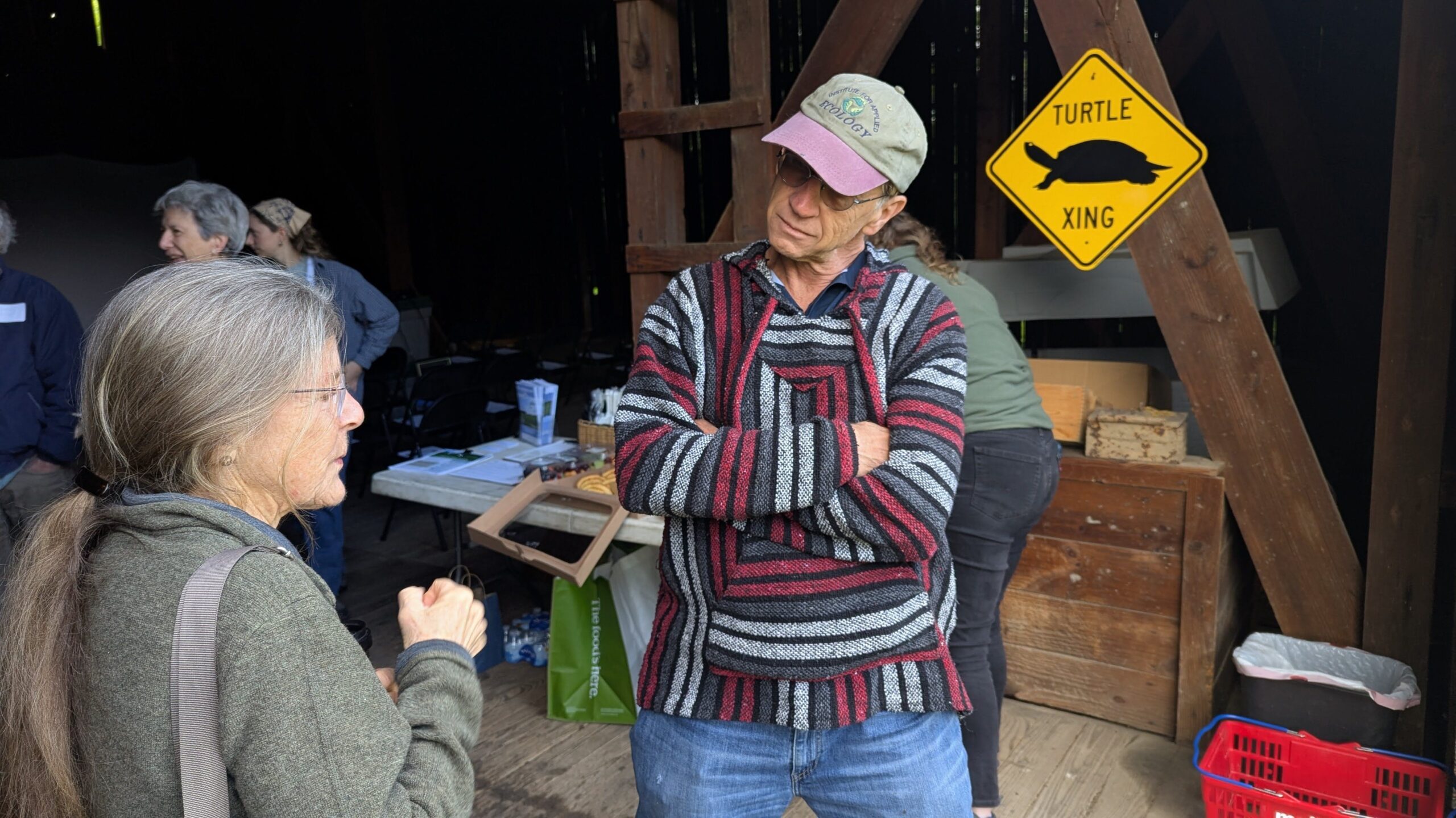 Man talking to a woman in a barn with a turtle xing sign behind them