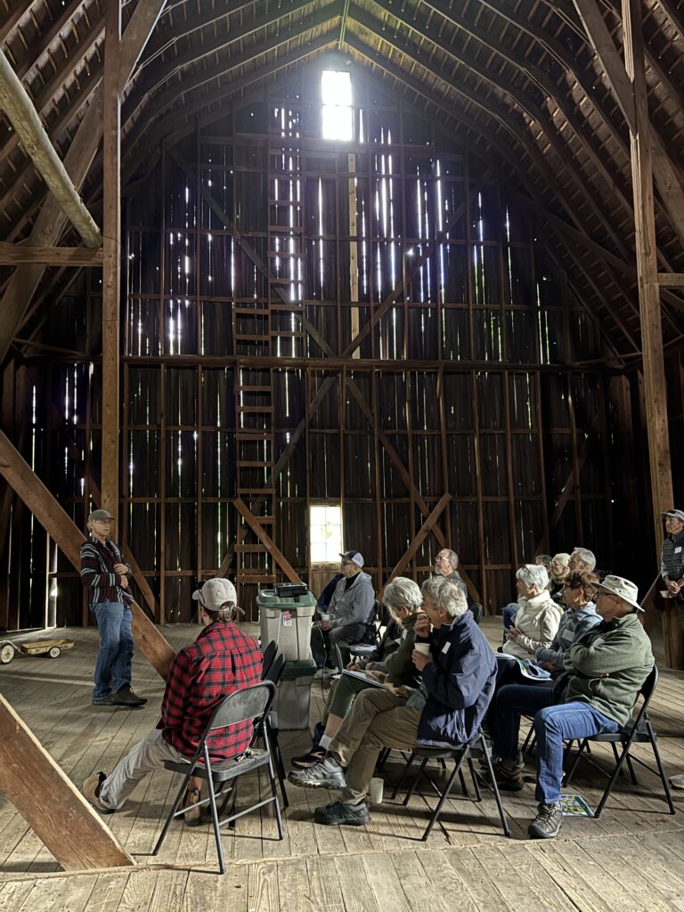 Man talking to group of people in a barn