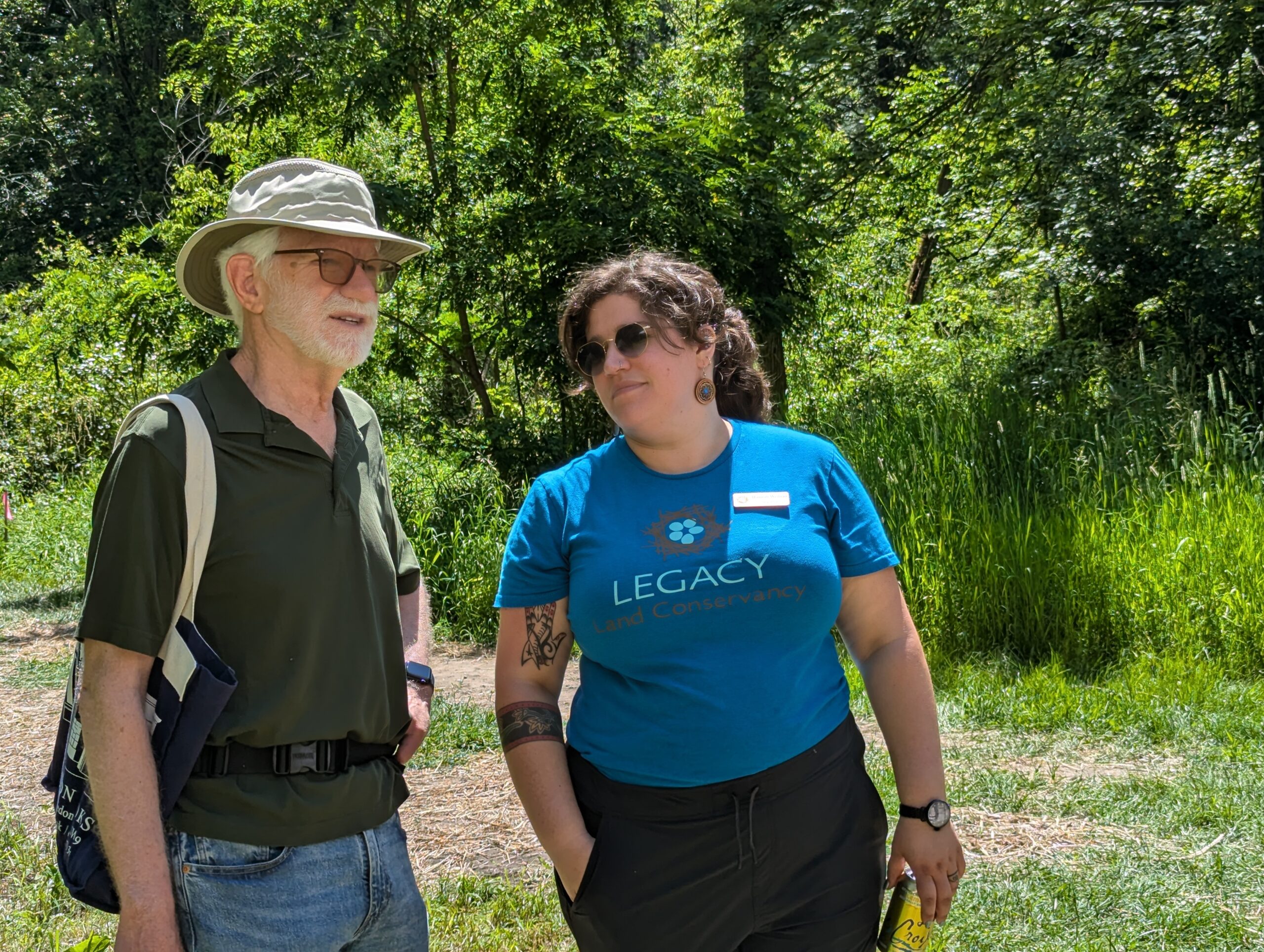 Two people talking in front of a tree lined trail
