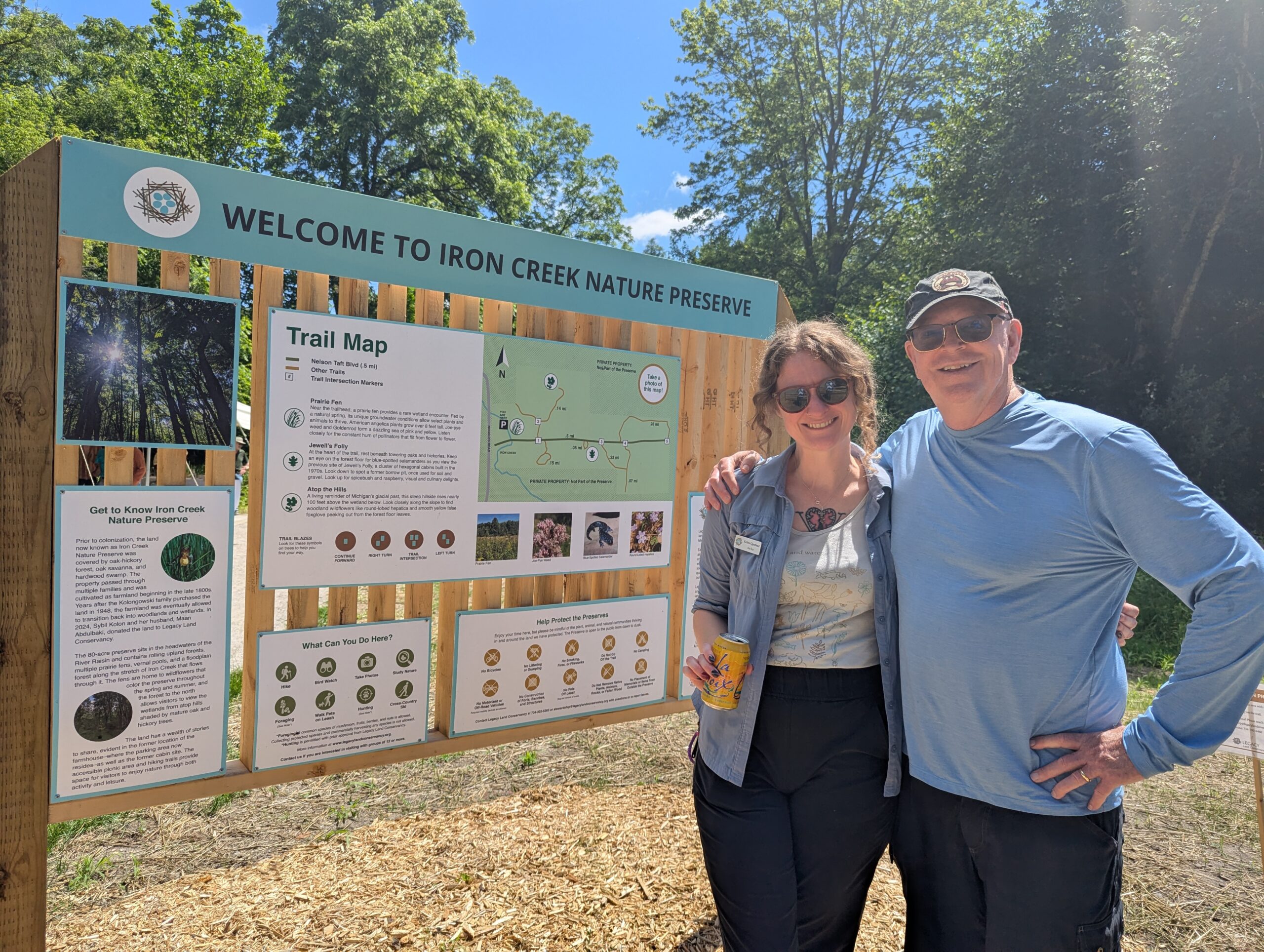 Two people stand next to Welcome to Iron Creek Nature Preserve kiosk