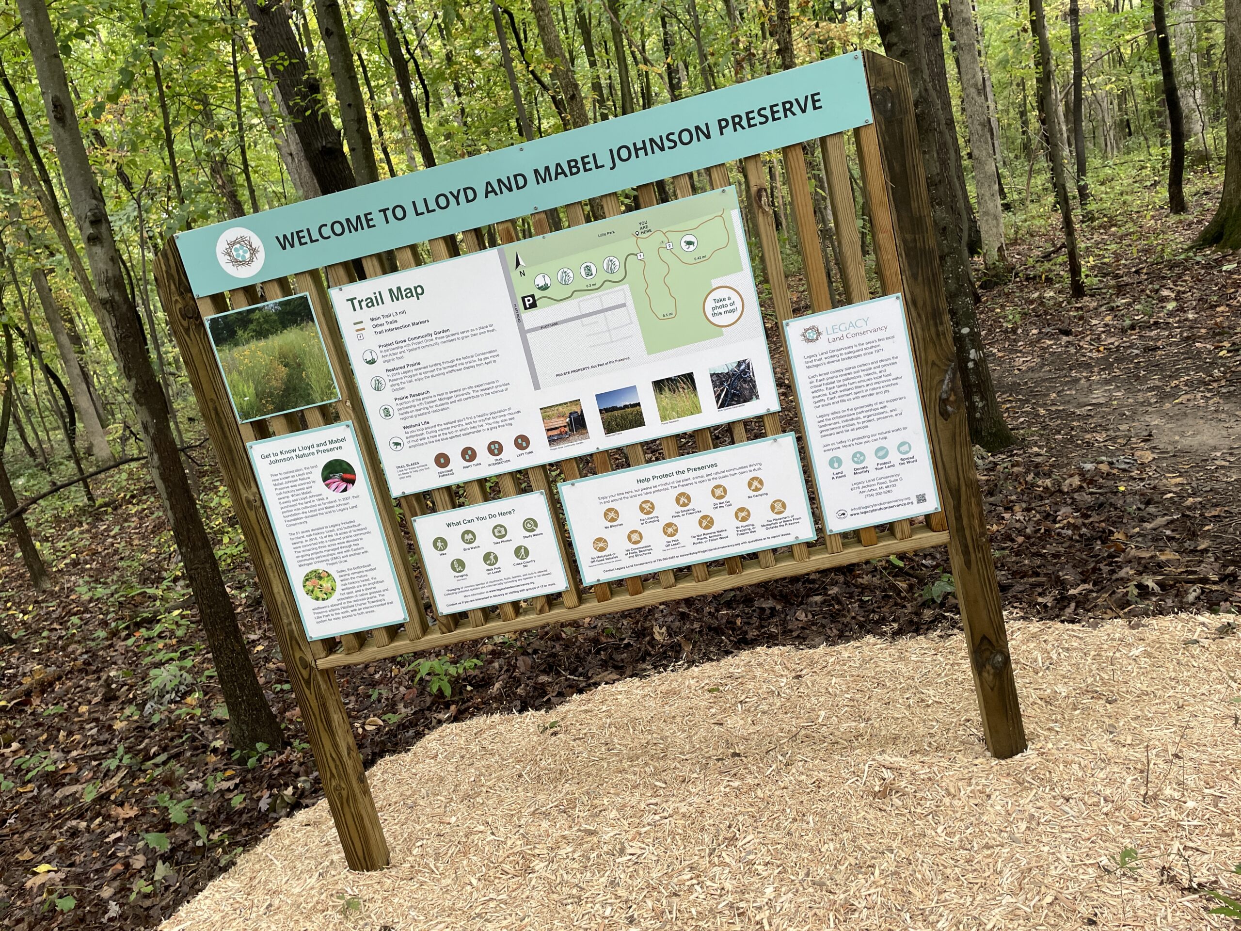 Wooden kiosk with multiple nature preserve information signs.